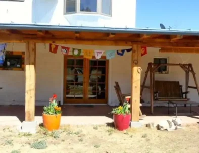 flag-lined front porch with swinging bench and rocking chair